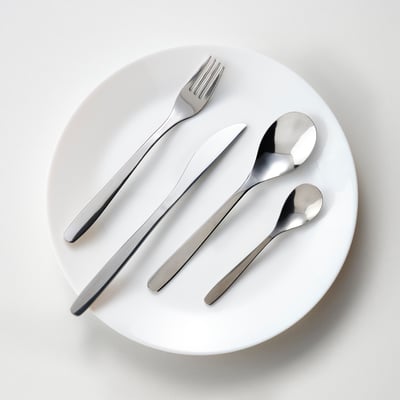 MOPSIG cutlery set: shiny steel fork, knife, spoon, and teaspoon on a white plate, modern minimalist design, durable and easy to clean.