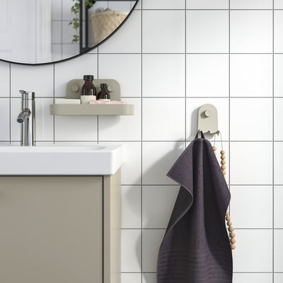 Modern grey bathroom with ÖBONÄS wall hook, grey towel, floating shelf, mirror, and tap.