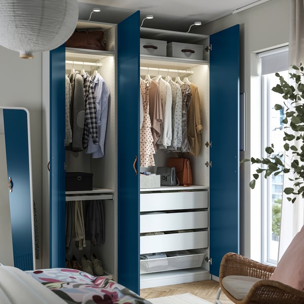 Open blue PAX wardrobe showing clothes, drawers, and shoe storage, with integrated lighting.