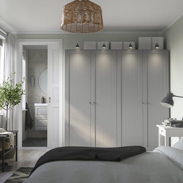 Minimalist bedroom with PAX wardrobe, wall lamps, bedside lamp, and corner bathroom sink.