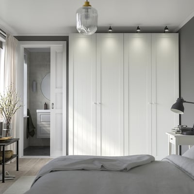 Modern bedroom with large PAX wardrobe, integrated lights, grey bedding.