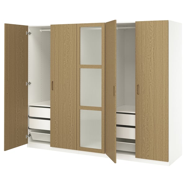An open wooden ikea PAX wardrobe in light oak, featuring shelves, drawers, and a hanging rail.