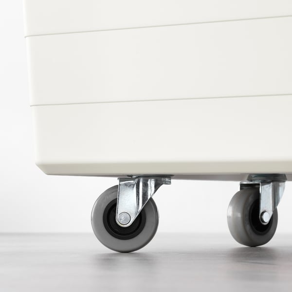 Close-up of white box with grey castors. Castors have brakes and plates for mounting.