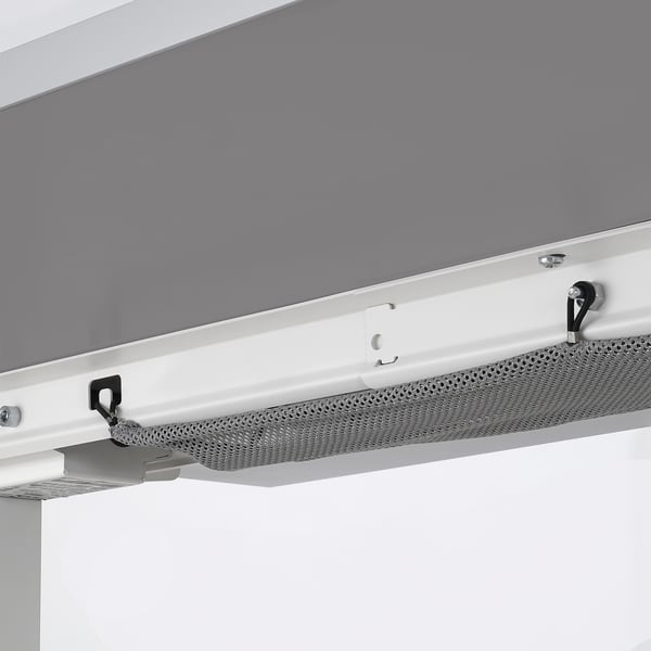 White adjustable office desk with feet for stability and cable management holes. Grey mesh panel visible.