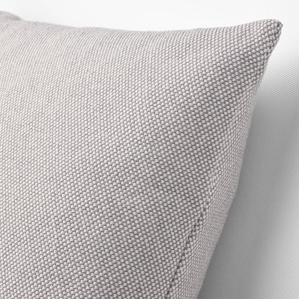 Close-up of textured, grey-white cushion on a chair, showing its intricate, knitted fabric and plump, feather-filled design.