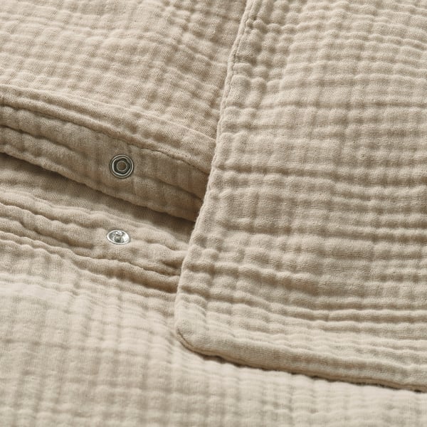 Folded beige duvet set made of soft, organic cotton with closure details visible.