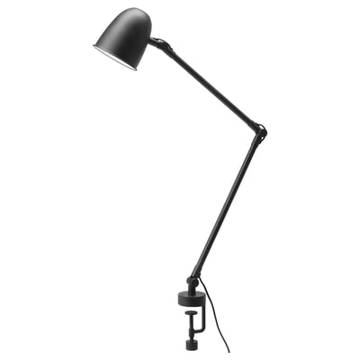 A black SKURUP lamp with an adjustable arm and shade, designed for versatile use as both a desk and wall lamp.