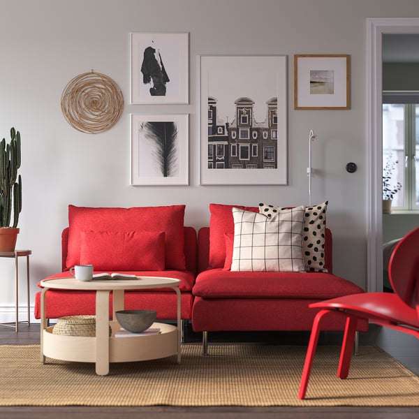 Red SÖDERHAMN sectional sofa with pillows, beige rug, gallery wall, coffee table with mug and bowl.