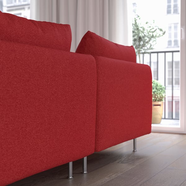 Red modern sofa with high legs in living space by window.