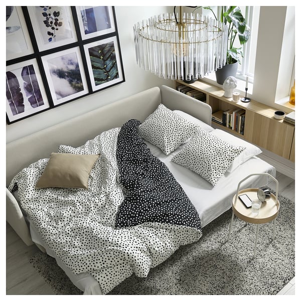 Modern living room featuring a white SÖDERHAMN sofa-bed with black and white dotty bedding, gold pillow, and stylish decor.