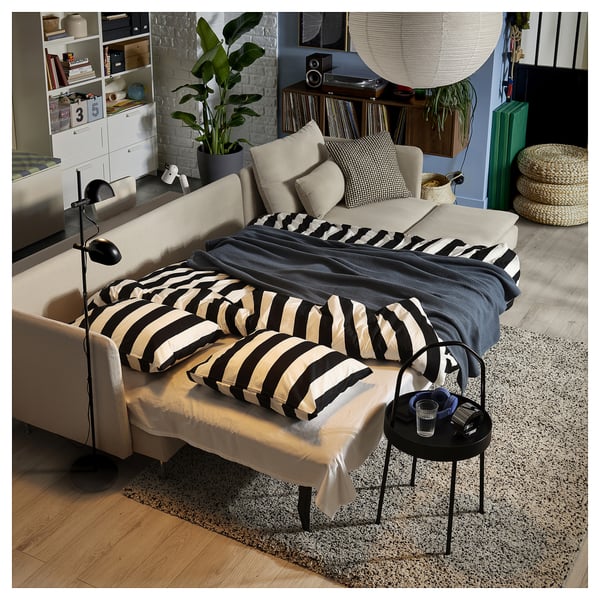 Beige SÖDERHAMN sofa-bed with black and white striped cushions in a cosy living room setting.
