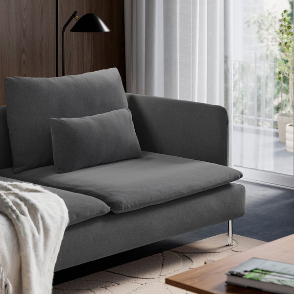 A modern, grey sofa with two cushions and a black floor lamp beside a large window, providing a cosy and well-lit sitting area.