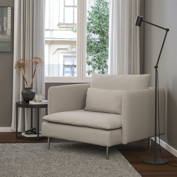 Modern neutral-toned chair near window, with side table and lamp.