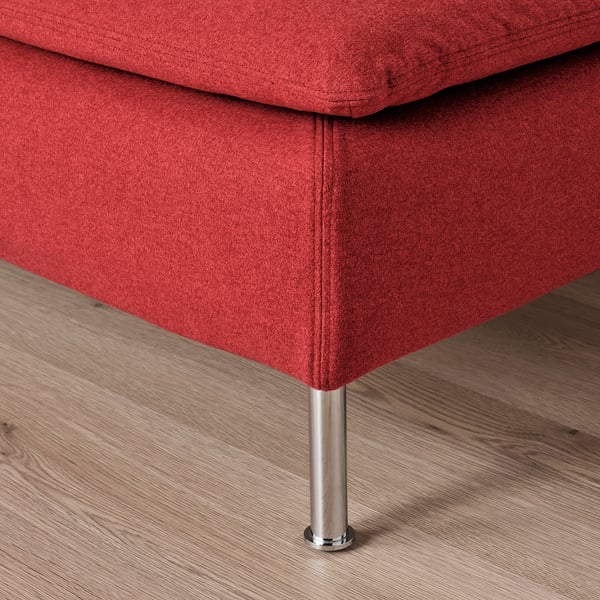 Red fabric sofa leg on wooden floor. Metal leg with round base.