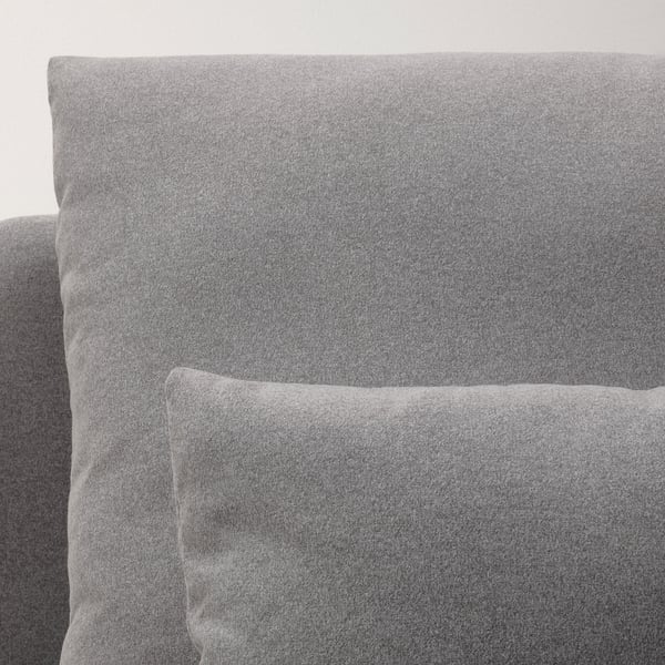 Close-up view of a modern, cushioned chaise longue in a neutral grey fabric, showcasing its soft, inviting texture and contemporary design.