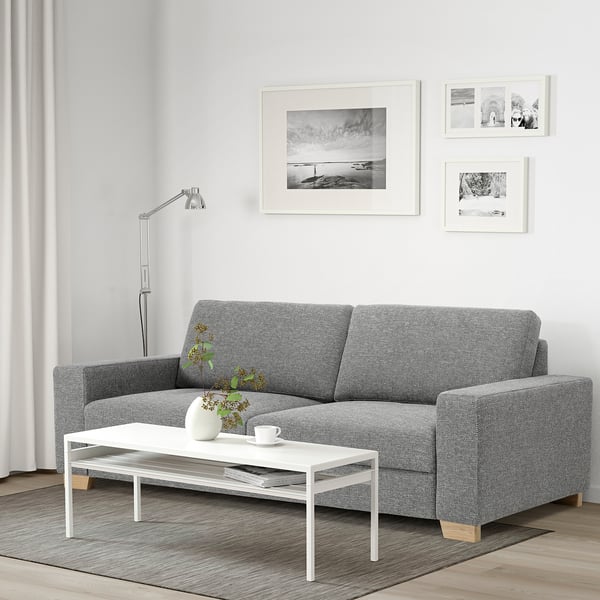 Minimalist living room with grey sofa, white table, wall art, lamp & photos.