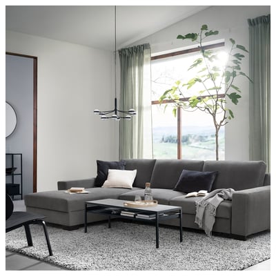 Modern living room with a dark grey SÖRVALLEN sectional sofa, black coffee table, large windows, and a tall green plant.