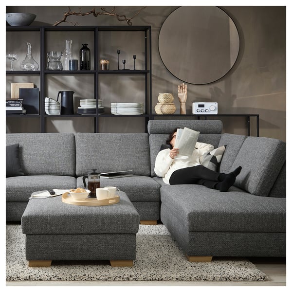 Modern living room with a grey SÖRVALLEN sectional sofa, ottoman, wood tray, cups, books, and decor on shelves.