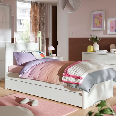 Modern white STORKLINTA bed, purple linens, drawers, pink walls.
