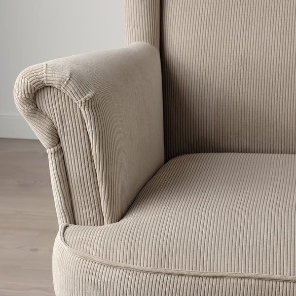 Close-up of beige STRANDMON chairs arm and side, showcasing soft, ribbed corduroy texture, comfortable design.