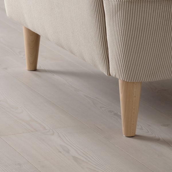 Comfy, modern chair with light, ribbed upholstery and wooden legs on a light wood floor.