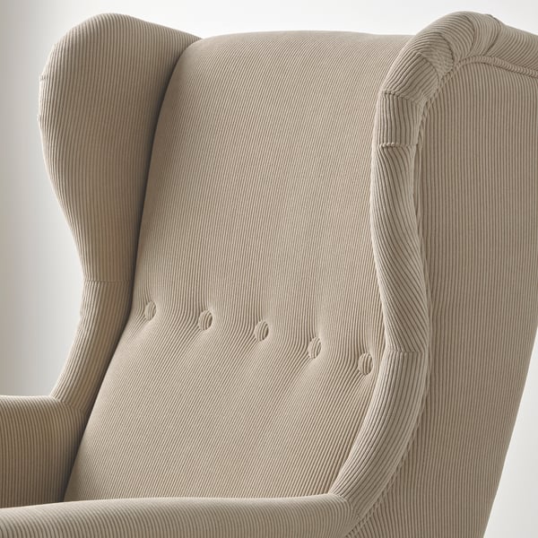 Close-up of a cosy STRANDMON armchair, showcasing its soft, textured upholstery and inviting design.