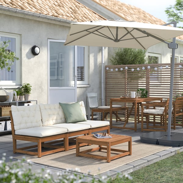 Cosy outdoor patio with wood couch, coffee table, and beige parasol.