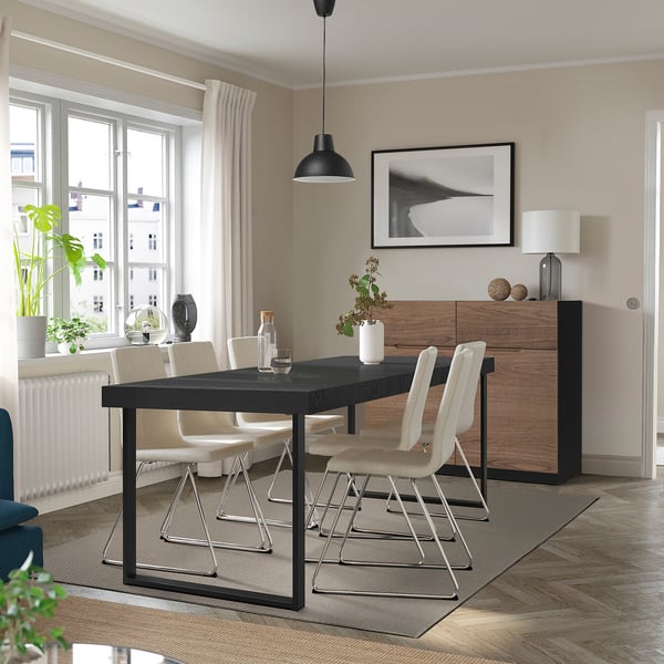 Modern dining room with black extendable table, beech chairs, and wooden cabinet.