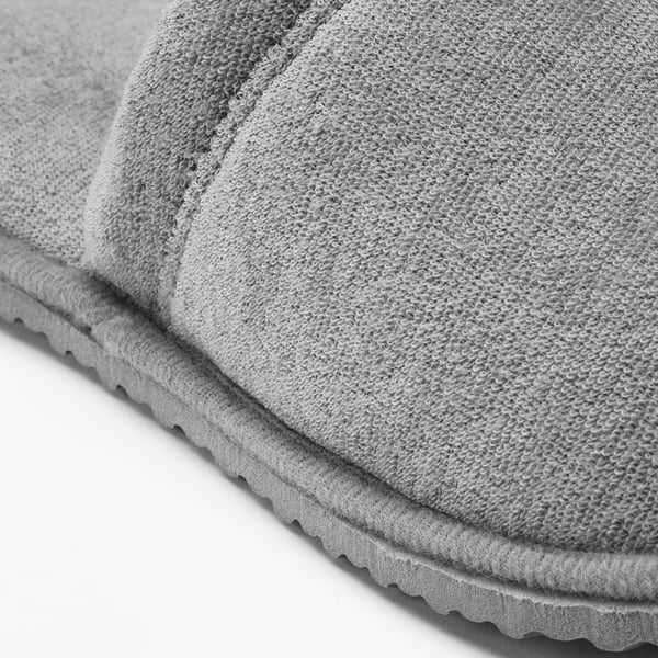 Grey slipper with textured knit fabric and scalloped sole, showing grip detail.