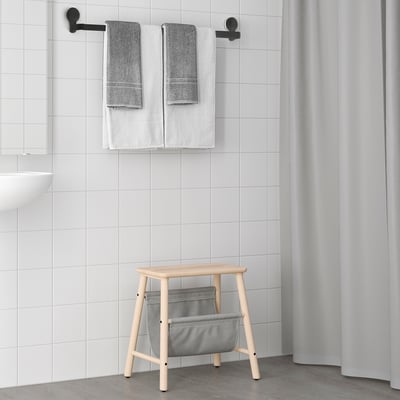 Modern bathroom with TISKEN towel rack and stool with bin beside white sink and shower.