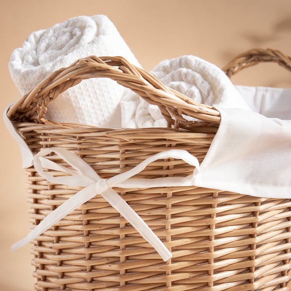 Handwoven willow laundry basket with white inner bag and ribbon, perfect for home use.
