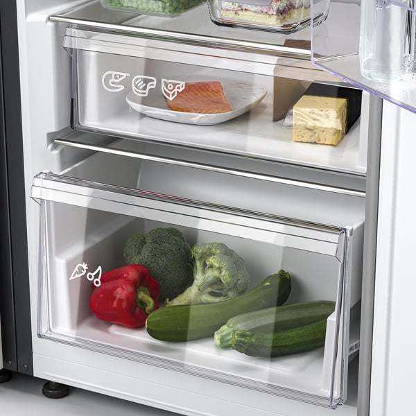 Open fridge with veggies in drawer: broccoli, pepper, courgette, plus fish on upper shelf.