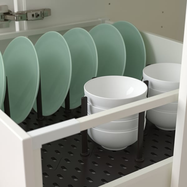 White cabinet with green plates and white bowls organised by adjustable pegs.