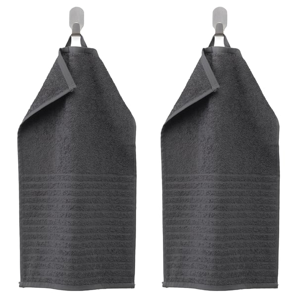 Two dark grey VÅGSJÖN towels hang side by side on hooks, featuring striped texture and folded tops.