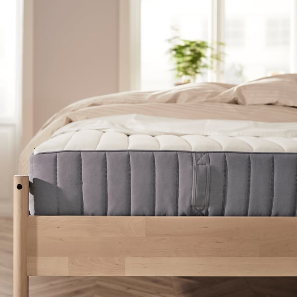 Minimalist bedroom with light-colored mattress on wooden bed frame.