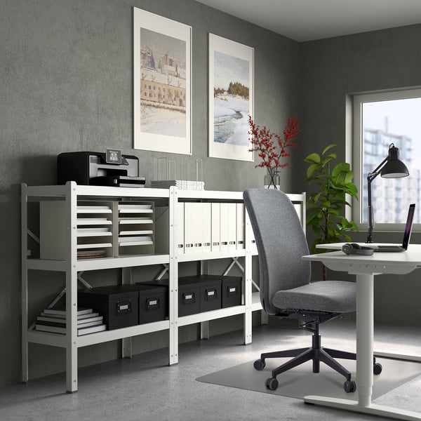 A minimalist white office setup with a gray chair, desk, printer shelf, and wall art.