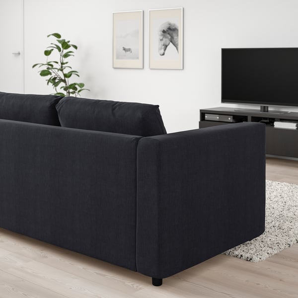 Modern living room with black VIMLE sofa, tv, wood floor, plant.