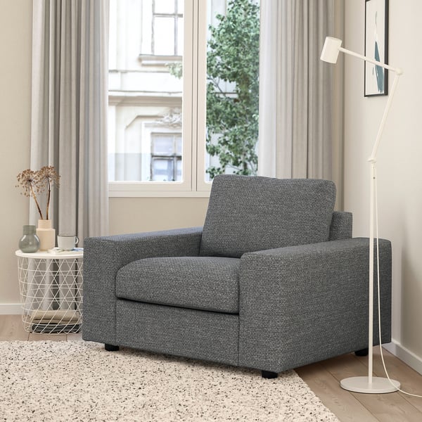 Grey VIMLE accent chair, lamp, side table with vases, by large window with curtains. Cosy, minimalist room with rug.