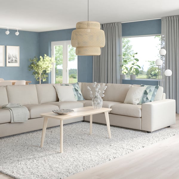 Modern living room with large beige VIMLE sectional sofa, light wood coffee table, and large window with blue curtains.
