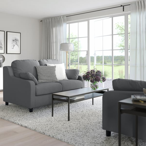 Modern living room with grey VINLIDEN sofa, glass coffee table, side table, and large window with curtains.