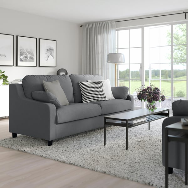 Modern living room with grey VINLIDEN sofa, cushions, and coffee table with flowers.