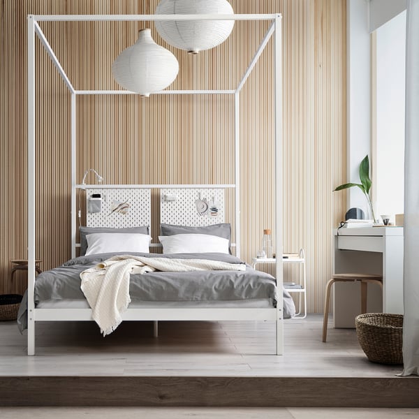 Minimalist bedroom with white VITARNA four-poster bed, matching furniture, hanging lamps, and greenery.