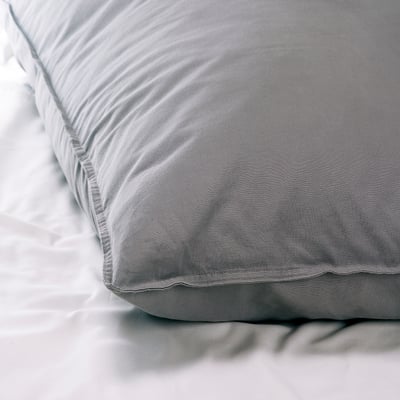 Soft, grey cotton bed sheet and pillowcase set on white bedding. High-quality, smooth fabric, inviting touch.