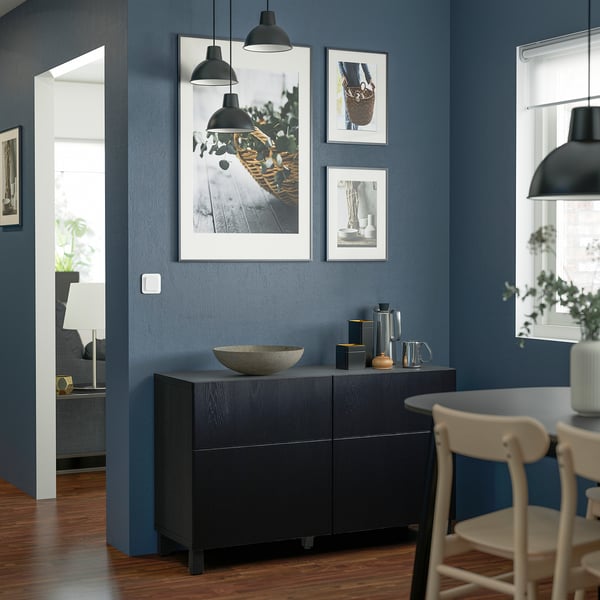 Modern dining room with dark blue walls, wooden floor, BESTÅ sideboard, chairs, and pendant lamps.