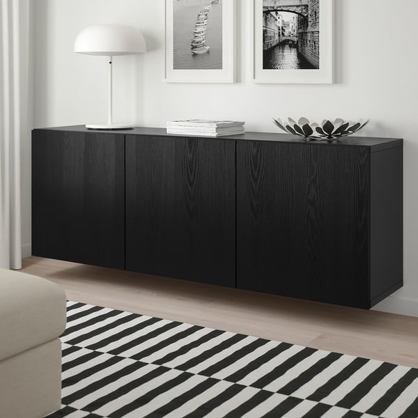 Modern living room with black BESTÅ sideboard, white lamp, striped rug, white sofa, above black wooden floor.