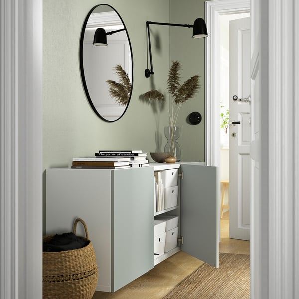 Entrance hallway storage: wall-mounted cabinet with mirror, lighting, flowers, books, and basket.