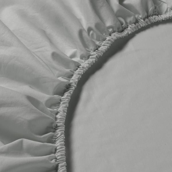Grey fitted sheet with elastic edges on a bed, highlighting its smooth cotton fabric.