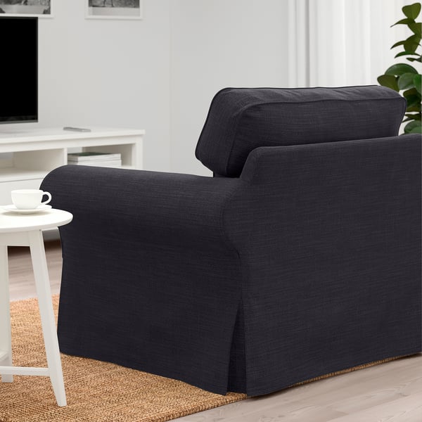 A dark grey EKTORP armchair in a living room, next to a white side table holding a coffee cup.