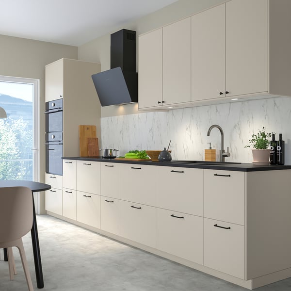 Modern kitchen with white FINSMAKARE oven, sleek countertops, black handles, grey floor, and large window.