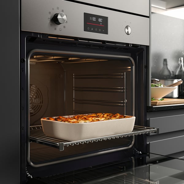 Stainless-steel oven with digital display baking lasagna, showing true fan cooking function.